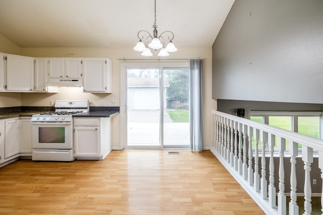 2316 SE 17th St, Des Moines, IA 50320 - kitchen with gas range gas stove, under cabinet range hood, lofted ceiling, dark countertops, and white cabinets