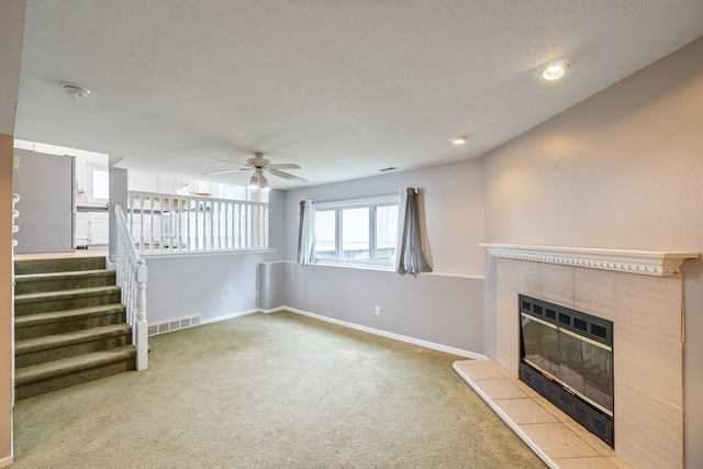 2316 SE 17th St, Des Moines, IA 50320 - unfurnished living room with a tiled fireplace, carpet floors, a ceiling fan, and stairway