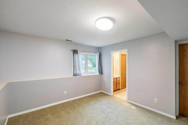 2316 SE 17th St, Des Moines, IA 50320 - unfurnished bedroom with light carpet, a textured ceiling, and ensuite bath