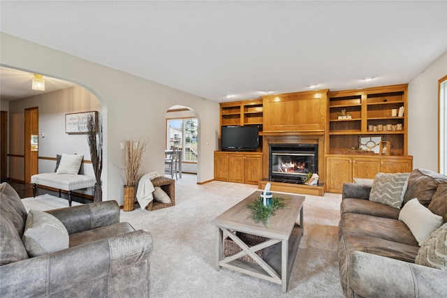 8001 Sheridan Dr, Urbandale, IA 50322 - living room with arched walkways, carpet floors, a glass covered fireplace, and built in shelves