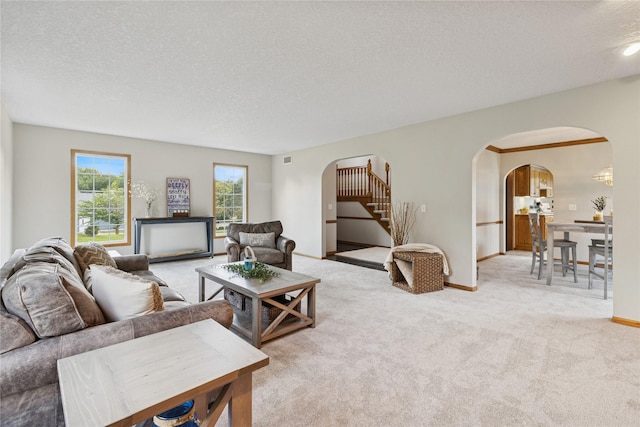 8001 Sheridan Dr, Urbandale, IA 50322 - living room featuring arched walkways, a textured ceiling, light carpet, and stairs