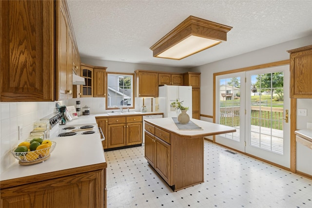 8001 Sheridan Dr, Urbandale, IA 50322 - kitchen featuring white appliances, under cabinet range hood, light countertops, a textured ceiling, and brown cabinets