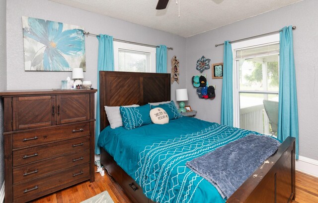 420 9th St, West Des Moines, IA 50265 - bedroom with light wood-style floors, a textured ceiling, multiple windows, and a ceiling fan