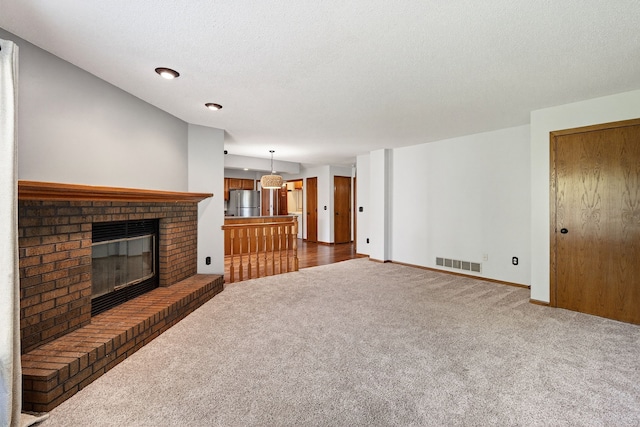 4719 84th St Unit A, Urbandale, IA 50322 - unfurnished living room with carpet, a brick fireplace, and a textured ceiling
