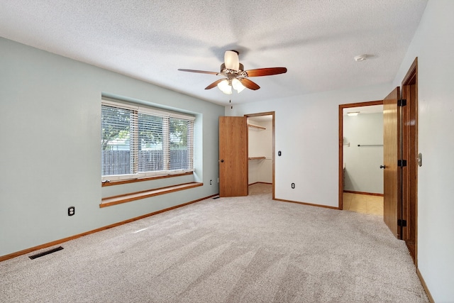 4719 84th St Unit A, Urbandale, IA 50322 - unfurnished bedroom featuring carpet, a textured ceiling, a spacious closet, and a ceiling fan