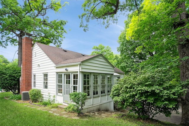 2625 38th St, Des Moines, IA 50310 - view of side of property featuring a chimney, a shingled roof, and a sunroom