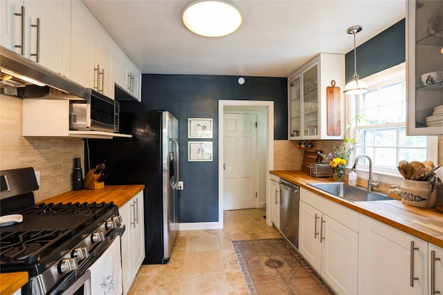 2625 38th St, Des Moines, IA 50310 - kitchen featuring butcher block countertops, stainless steel appliances, glass insert cabinets, backsplash, and white cabinets