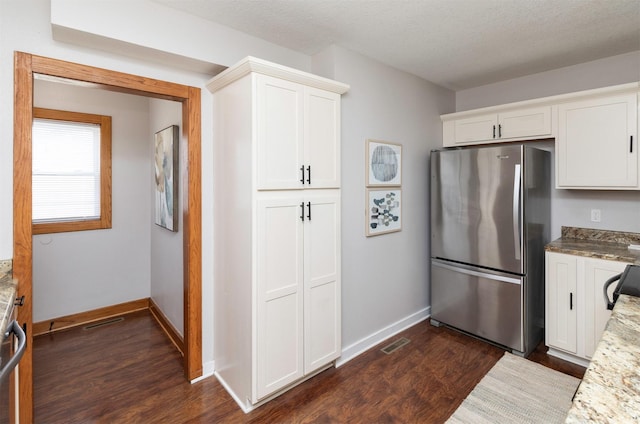 3948 43rd St, Des Moines, IA 50310 - kitchen with freestanding refrigerator, dark wood-type flooring, white cabinets, and light stone counters