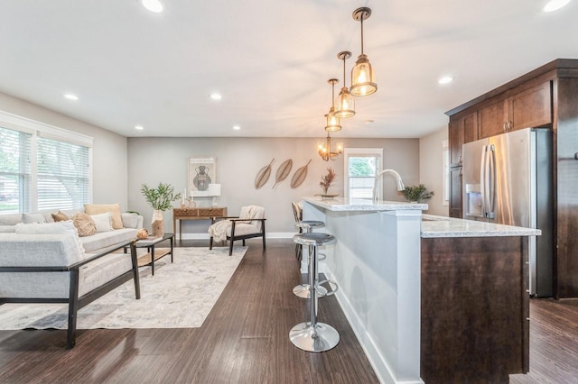 3817 80th St, Urbandale, IA 50322 - kitchen with stainless steel fridge with ice dispenser, light stone counters, recessed lighting, decorative light fixtures, and a kitchen island with sink