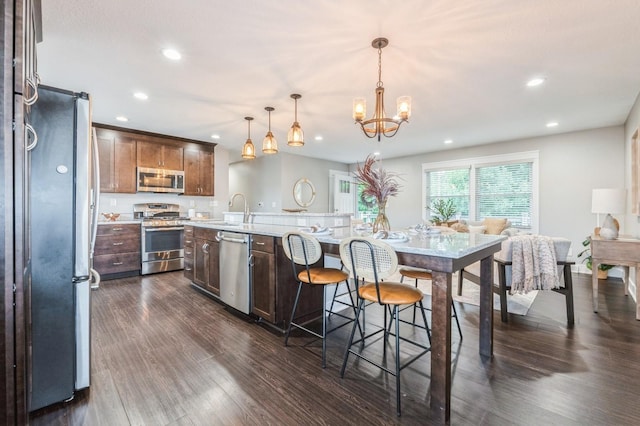 3817 80th St, Urbandale, IA 50322 - kitchen with appliances with stainless steel finishes, recessed lighting, dark wood-style floors, a center island with sink, and a chandelier