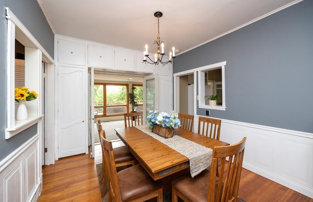 2418 Terrace Rd, Des Moines, IA 50312 - dining space with a chandelier, ornamental molding, light wood-style flooring, wainscoting, and a decorative wall