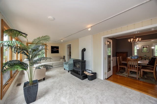2418 Terrace Rd, Des Moines, IA 50312 - living room featuring a wood stove, carpet floors, and a chandelier