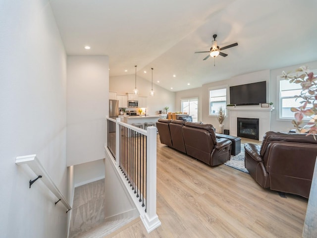 645 NW Prairie Rose Ln, Waukee, IA 50263 - living area with plenty of natural light, light wood finished floors, ceiling fan, lofted ceiling, and a glass covered fireplace