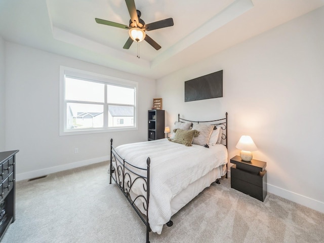 645 NW Prairie Rose Ln, Waukee, IA 50263 - bedroom with light carpet, a tray ceiling, and ceiling fan