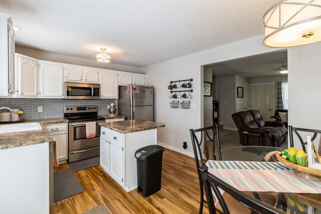 276 NW Georgetown Blvd, Ankeny, IA 50023 - kitchen with stainless steel appliances, wood finished floors, white cabinetry, backsplash, and a center island