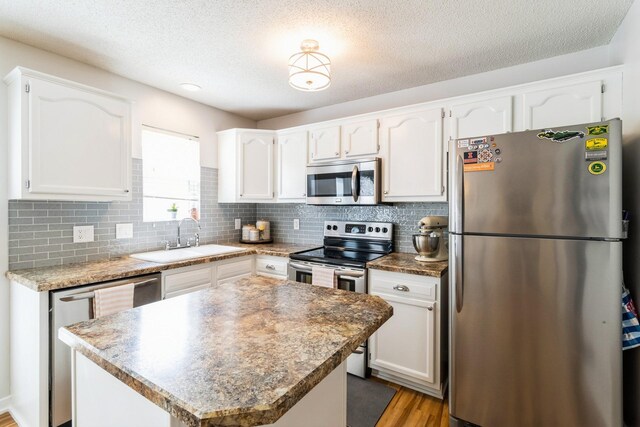 276 NW Georgetown Blvd, Ankeny, IA 50023 - kitchen with appliances with stainless steel finishes, white cabinetry, light wood-type flooring, tasteful backsplash, and a textured ceiling
