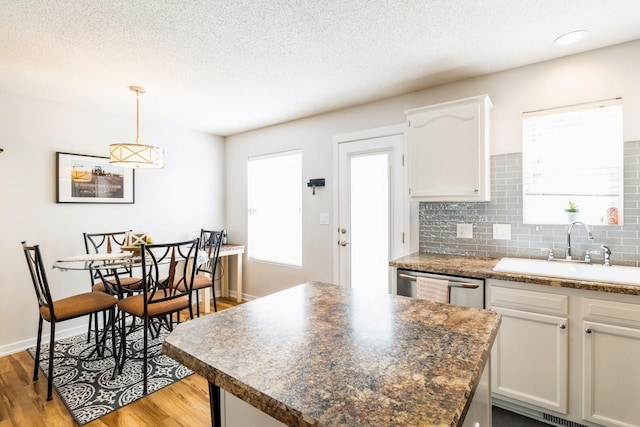 276 NW Georgetown Blvd, Ankeny, IA 50023 - kitchen featuring light wood-type flooring, white cabinetry, a textured ceiling, backsplash, and decorative light fixtures