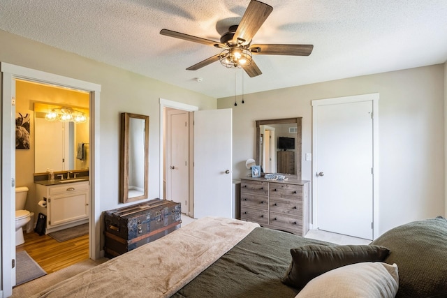 276 NW Georgetown Blvd, Ankeny, IA 50023 - bedroom with wood finished floors, ensuite bathroom, a textured ceiling, and a ceiling fan