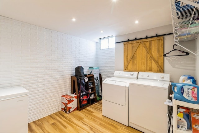 276 NW Georgetown Blvd, Ankeny, IA 50023 - washroom featuring washing machine and clothes dryer, brick wall, light wood-style flooring, and recessed lighting