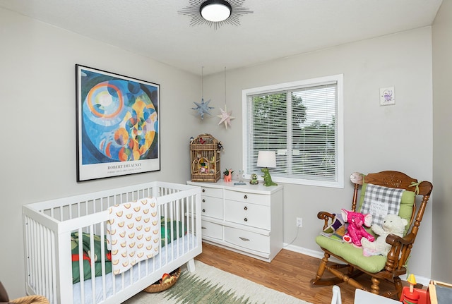 21 E Payton Ave, Des Moines, IA 50315 - bedroom featuring wood finished floors and a crib