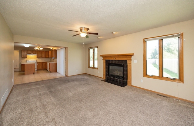 7523 Aspen Dr, West Des Moines, IA 50266 - unfurnished living room with a tile fireplace, light colored carpet, ceiling fan, and a textured ceiling