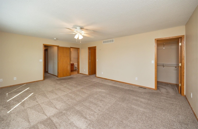 7523 Aspen Dr, West Des Moines, IA 50266 - unfurnished bedroom featuring a spacious closet, light carpet, a closet, a ceiling fan, and a textured ceiling