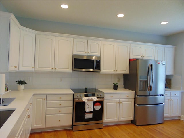 8114 Cobblestone Ct, Urbandale, IA 50322 - kitchen featuring stainless steel appliances, white cabinets, light wood-type flooring, backsplash, and recessed lighting