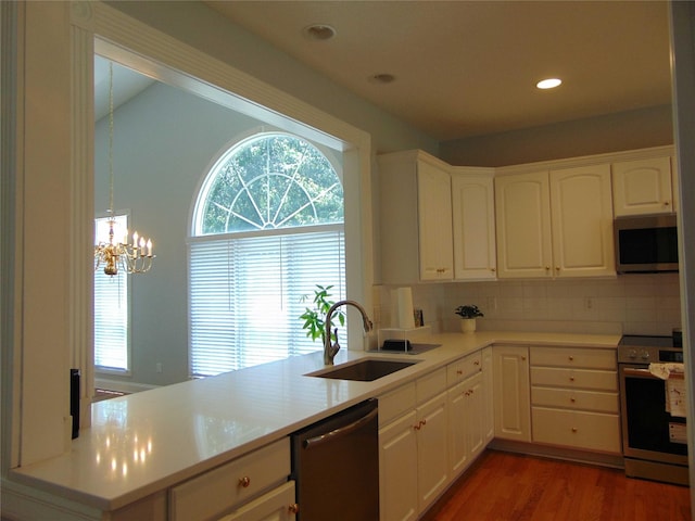 8114 Cobblestone Ct, Urbandale, IA 50322 - kitchen with appliances with stainless steel finishes, wood finished floors, a chandelier, white cabinetry, and light countertops