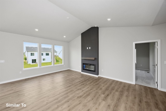 605 NW Compass Ave, Waukee, IA 50263 - unfurnished living room with wood finished floors, vaulted ceiling, a large fireplace, and recessed lighting