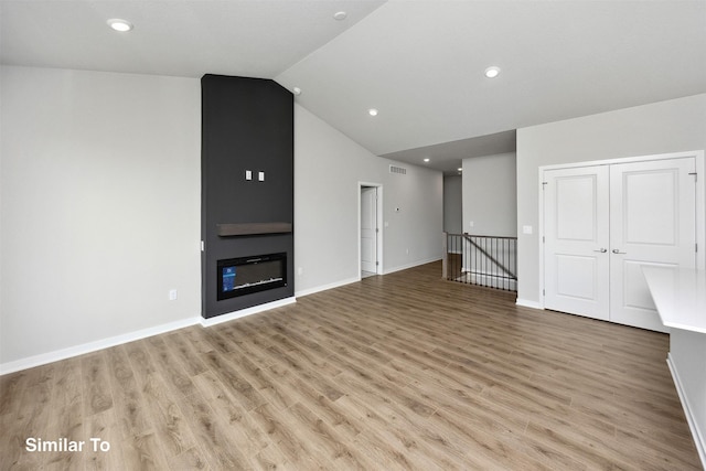 605 NW Compass Ave, Waukee, IA 50263 - unfurnished living room featuring light wood-style flooring, vaulted ceiling, a fireplace, and recessed lighting