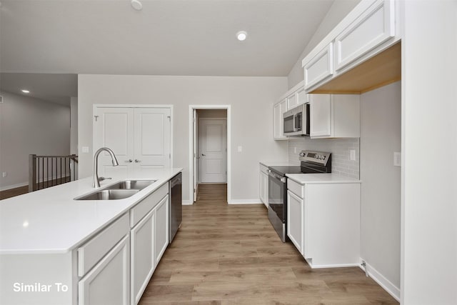 605 NW Compass Ave, Waukee, IA 50263 - kitchen with appliances with stainless steel finishes, white cabinetry, light countertops, a center island with sink, and light wood finished floors