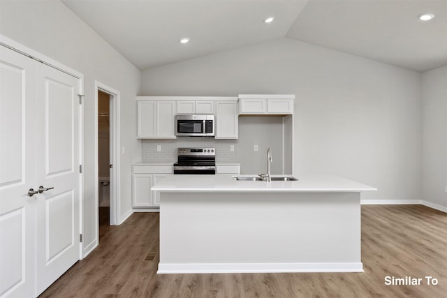 1163 NW Petersen Dr, Waukee, IA 50263 - kitchen with appliances with stainless steel finishes, white cabinets, light wood-style flooring, a kitchen island with sink, and light countertops