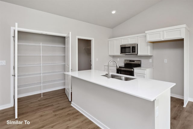 1163 NW Petersen Dr, Waukee, IA 50263 - kitchen with stainless steel appliances, light wood finished floors, vaulted ceiling, white cabinetry, and tasteful backsplash