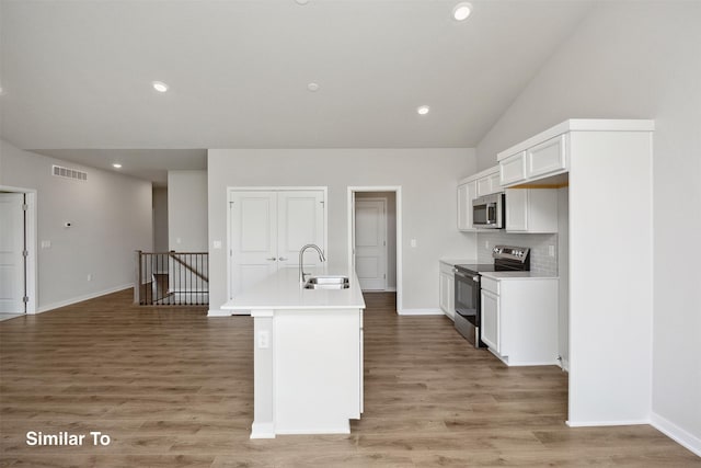 1163 NW Petersen Dr, Waukee, IA 50263 - kitchen with appliances with stainless steel finishes, an island with sink, light wood-style flooring, white cabinets, and light countertops