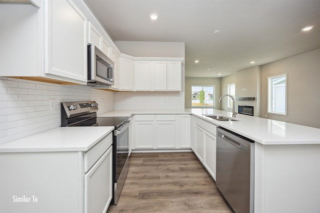 9756 Regatta Ln, Johnston, IA 50131 - kitchen with stainless steel appliances, a peninsula, light wood finished floors, white cabinets, and recessed lighting