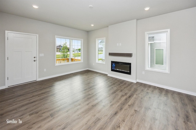 9756 Regatta Ln, Johnston, IA 50131 - unfurnished living room with wood finished floors, a glass covered fireplace, and recessed lighting