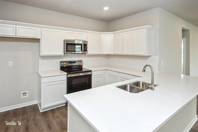 9764 Regatta Ln, Johnston, IA 50131 - kitchen featuring appliances with stainless steel finishes, a peninsula, dark wood-style flooring, white cabinets, and recessed lighting