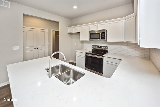 9764 Regatta Ln, Johnston, IA 50131 - kitchen with appliances with stainless steel finishes, white cabinets, tasteful backsplash, dark wood-type flooring, and light stone counters