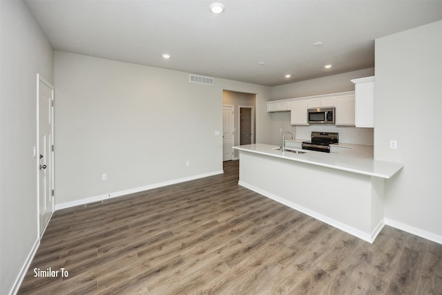 9764 Regatta Ln, Johnston, IA 50131 - kitchen featuring appliances with stainless steel finishes, white cabinets, light countertops, wood finished floors, and recessed lighting
