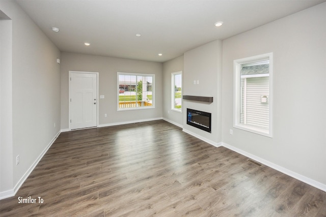9764 Regatta Ln, Johnston, IA 50131 - unfurnished living room with dark wood-type flooring, a glass covered fireplace, and recessed lighting