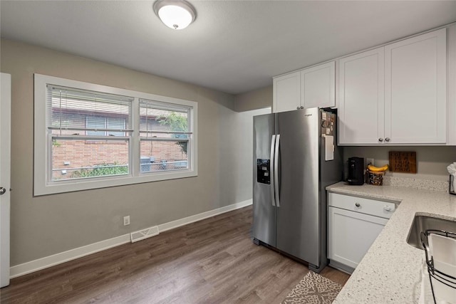 3415 Eastwood Dr, Des Moines, IA 50317 - kitchen featuring stainless steel fridge, wood finished floors, and white cabinets