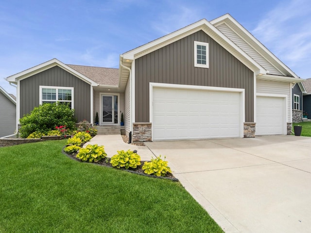 712 Mallard Pointe Dr NW, Bondurant, IA 50035 - view of front facade featuring a garage, driveway, stone siding, a front lawn, and board and batten siding