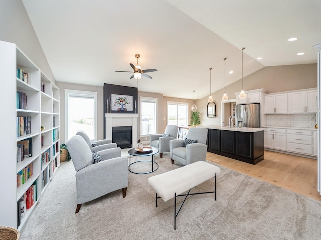 712 Mallard Pointe Dr NW, Bondurant, IA 50035 - living room with vaulted ceiling, plenty of natural light, a ceiling fan, a glass covered fireplace, and light wood-style flooring