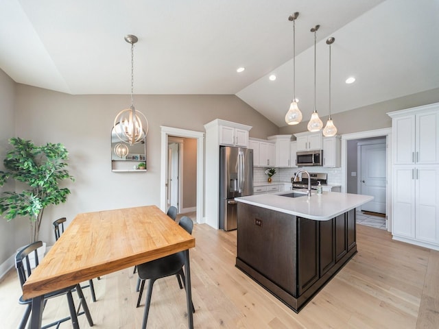 712 Mallard Pointe Dr NW, Bondurant, IA 50035 - kitchen featuring stainless steel appliances, light countertops, vaulted ceiling, white cabinets, and backsplash