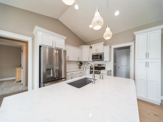 712 Mallard Pointe Dr NW, Bondurant, IA 50035 - kitchen featuring appliances with stainless steel finishes, vaulted ceiling, white cabinets, decorative backsplash, and hanging light fixtures