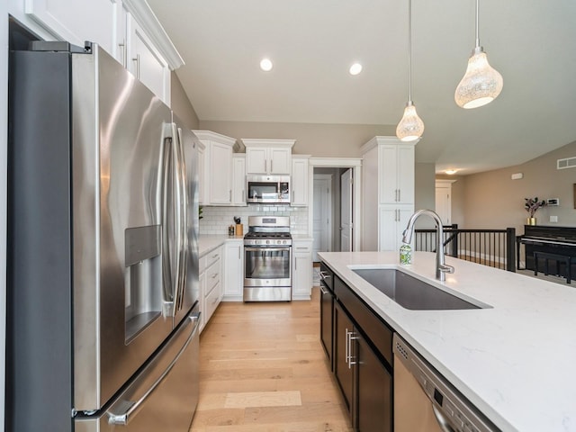 712 Mallard Pointe Dr NW, Bondurant, IA 50035 - kitchen featuring appliances with stainless steel finishes, white cabinets, light wood finished floors, decorative light fixtures, and recessed lighting