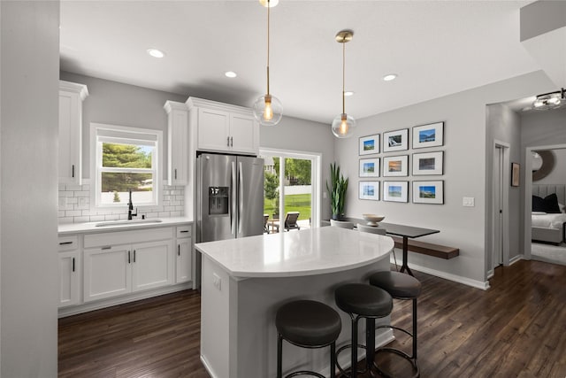 9622 NW 70th Ave, Johnston, IA 50131 - kitchen with stainless steel refrigerator with ice dispenser, dark wood-style floors, decorative backsplash, white cabinetry, and a kitchen island