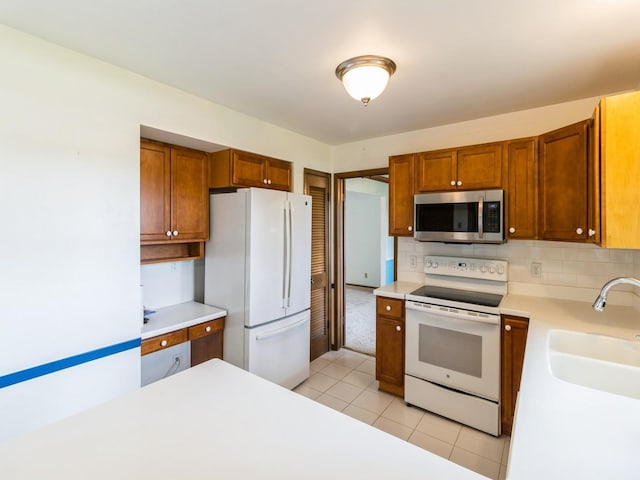 2100 Meadow Brook Dr, West Des Moines, IA 50265 - kitchen with white appliances, light countertops, light tile patterned floors, and brown cabinets