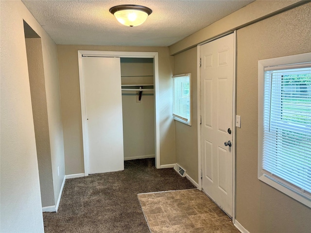 1431 E 19th St, Des Moines, IA 50316 - unfurnished bedroom with a closet, a textured ceiling, multiple windows, and carpet