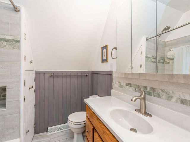 110 E 20th St N, Newton, IA 50208 - bathroom with vanity, a tile shower, lofted ceiling, and wainscoting